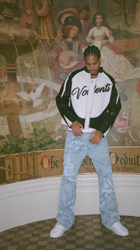 Person wearing a black and white jacket with 'Valentino' branding in a room with decorative wall art.