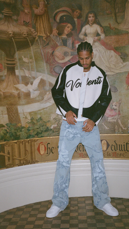 Person wearing a black and white jacket with 'Valentino' branding in a room with decorative wall art.